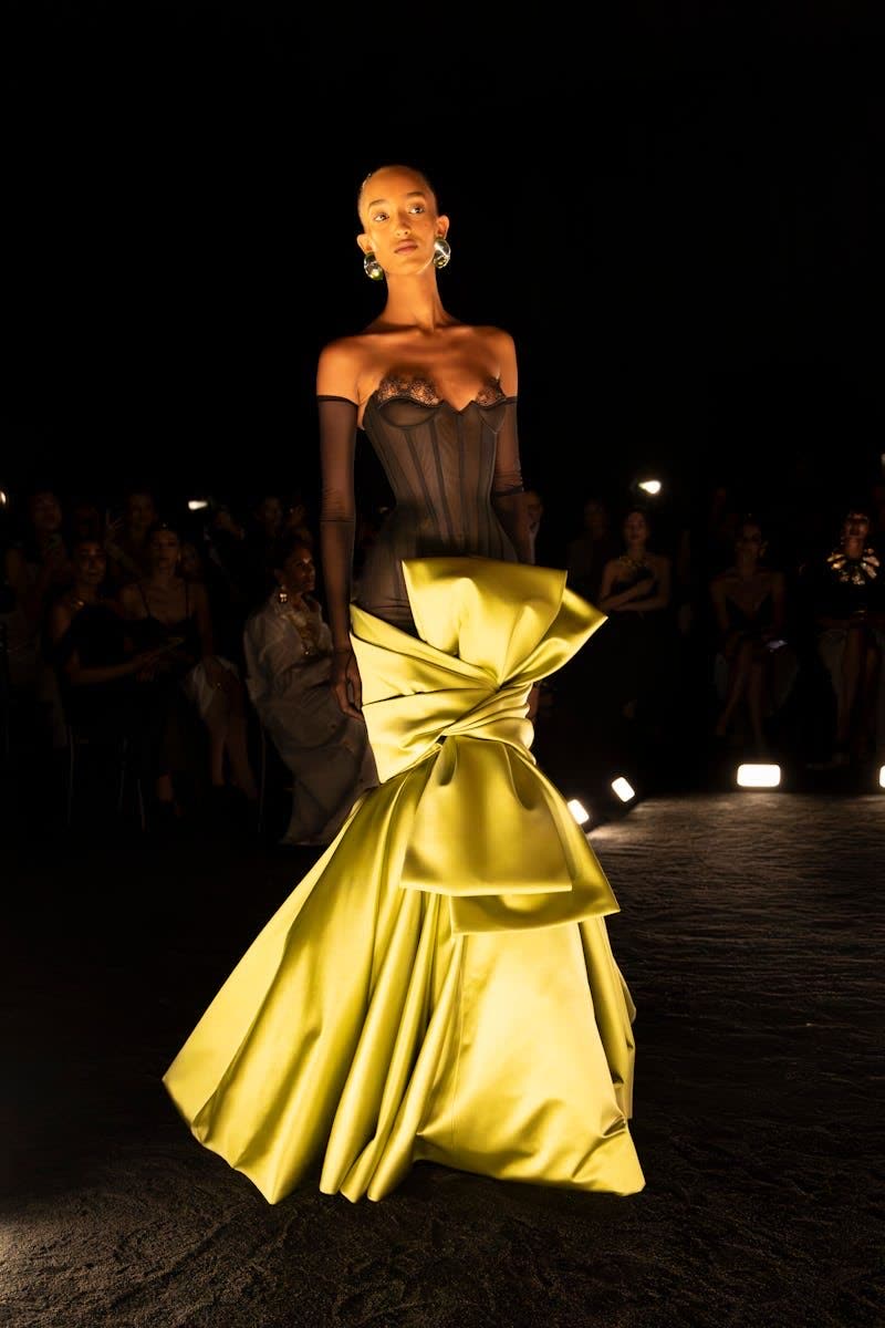 Model in a canary yellow satin gown with a dramatic sculpted bow