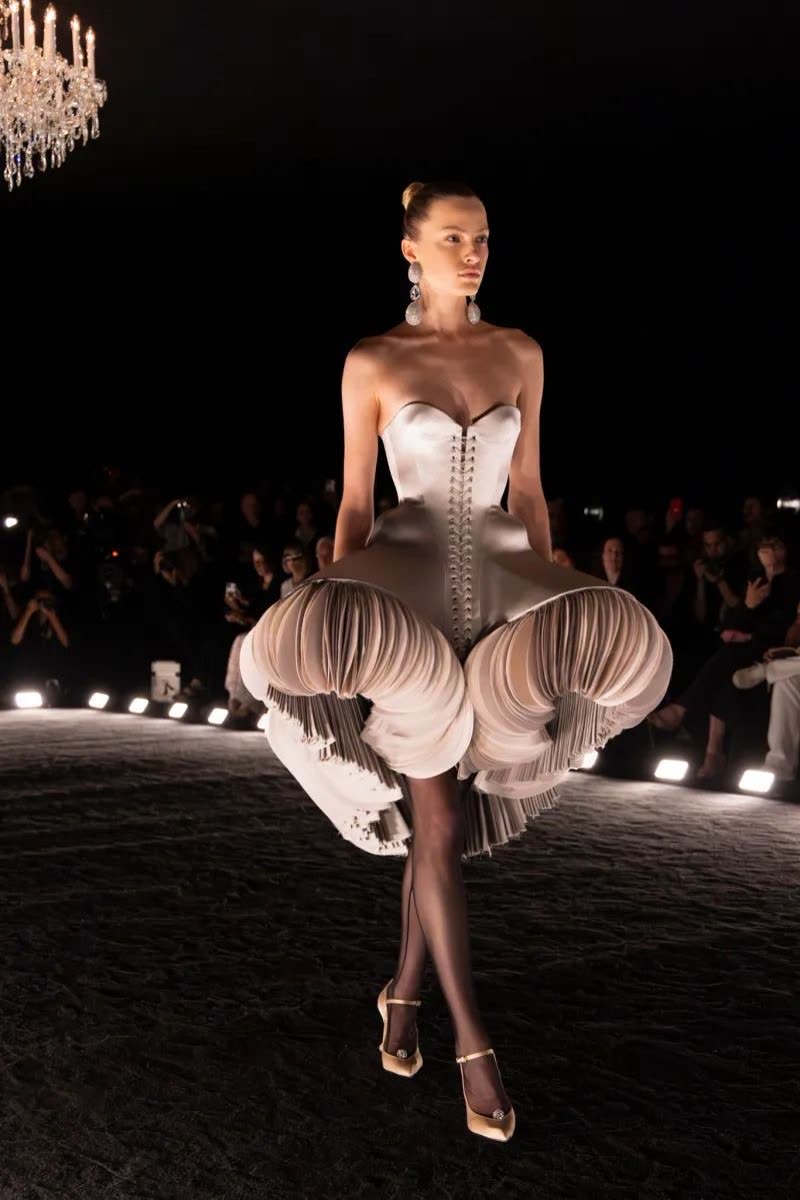 Ivory corset dress with a sculpted petal skirt on the runway