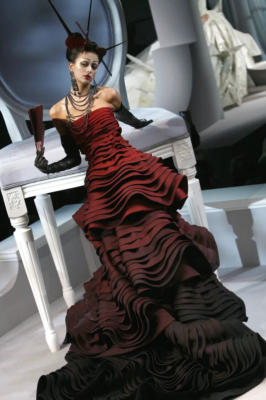 Deep red ruffled couture gown with elbow gloves and pearls